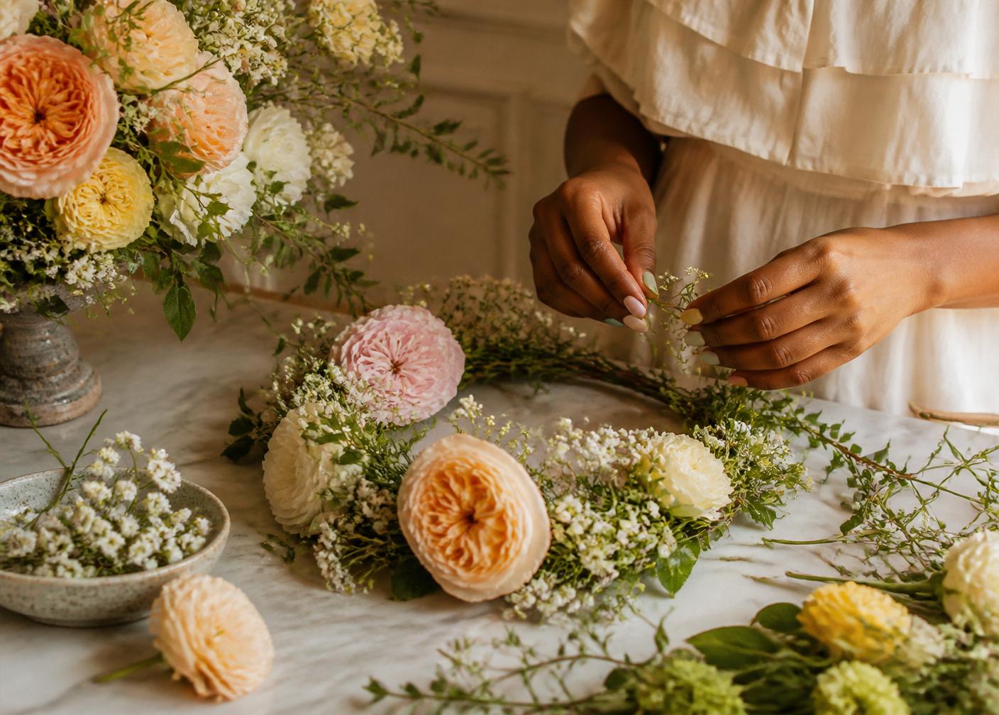 Hands crafting a delicate flower crown with garden roses and baby's breath